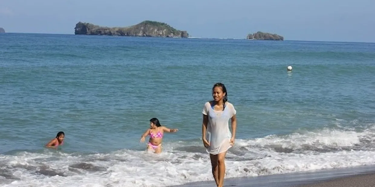 A woman and child in the water at the beach.