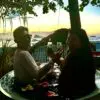 Two people sitting in a bowl holding wine glasses.