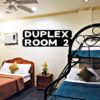 A photo of a hotel room with two beds and a bunk bed.
