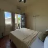 A bedroom with a bed, chair and window.