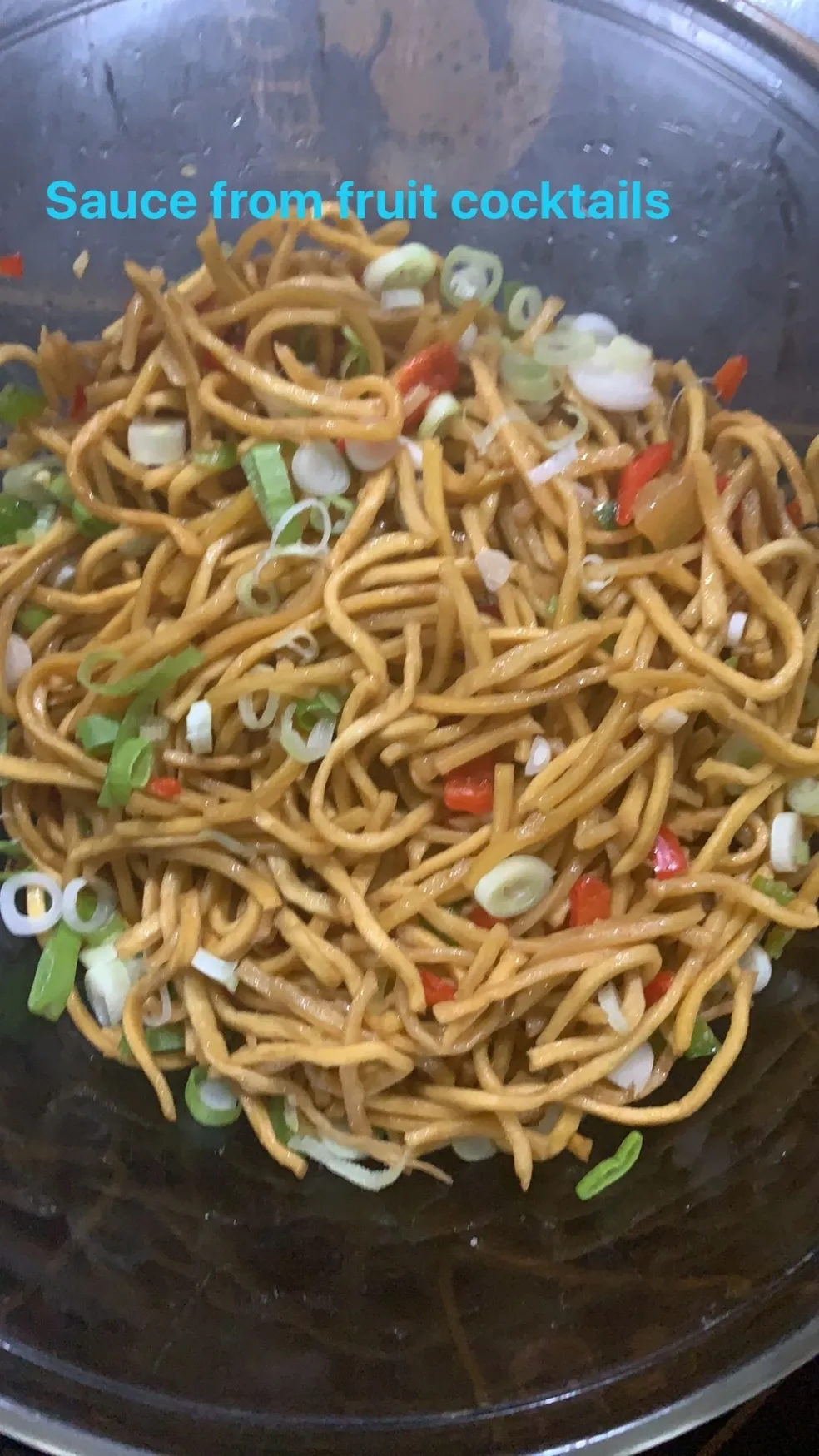 A bowl of noodles with onions and peppers.