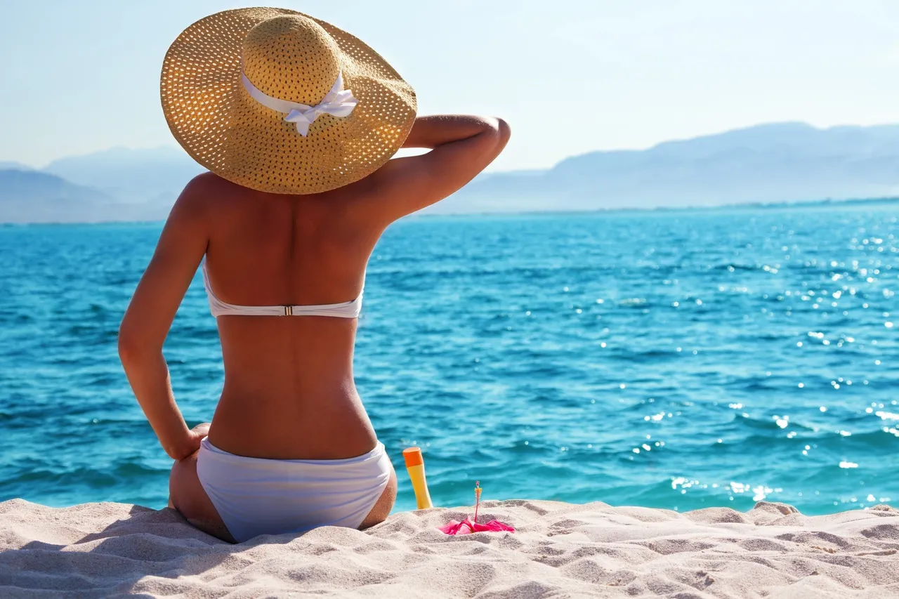 A woman sitting on the beach in her bikini