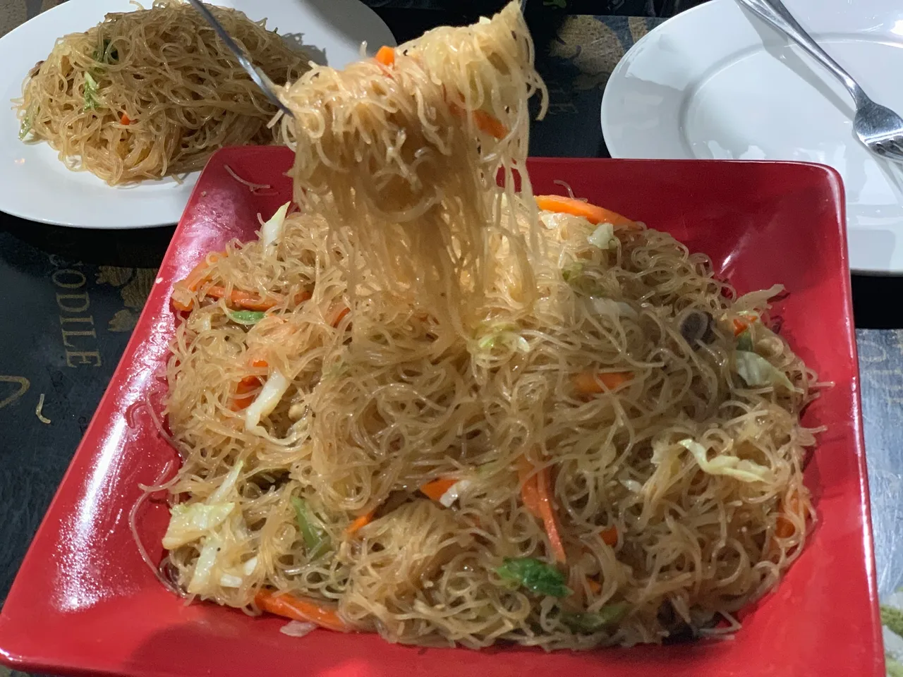 A red plate topped with noodles and vegetables.