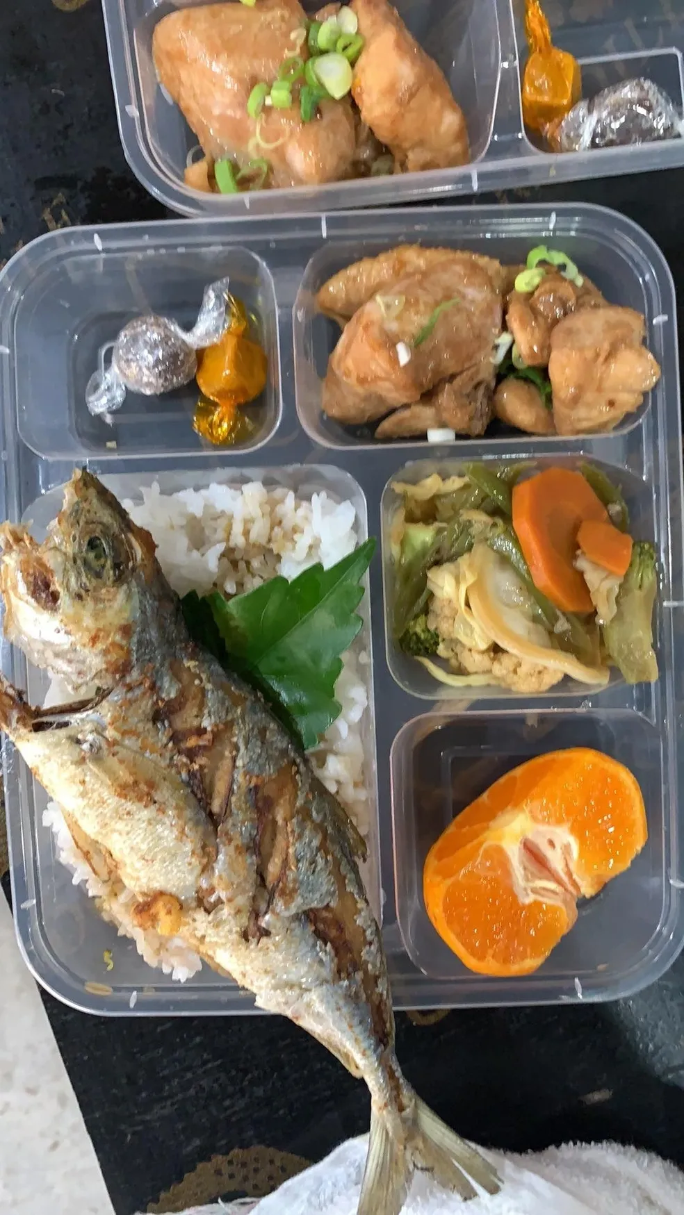 A tray of food with fish, rice and vegetables.