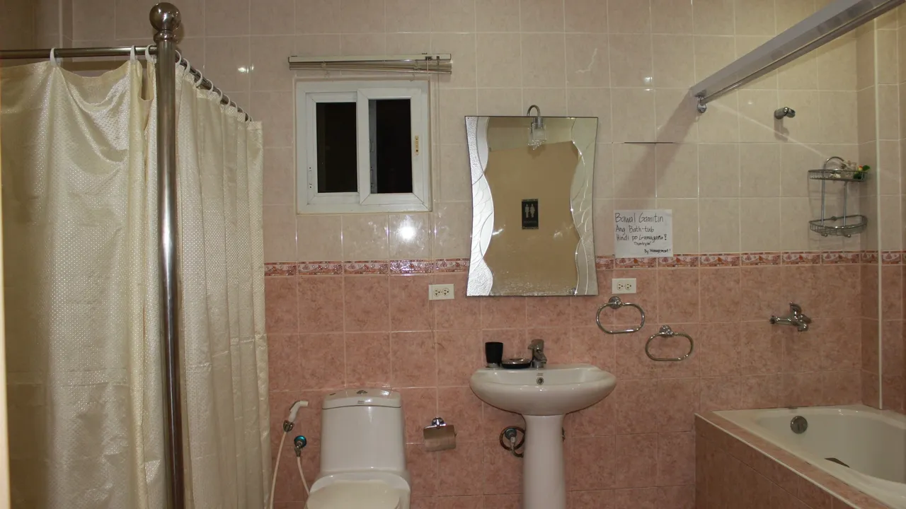 A bathroom with pink tile and white fixtures.