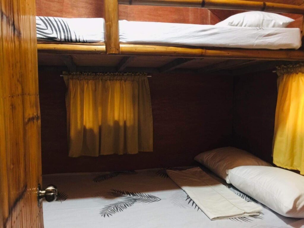 A bunk bed with white pillows and yellow curtains.