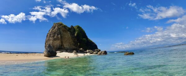 Rocky beach with blue water and white sand.