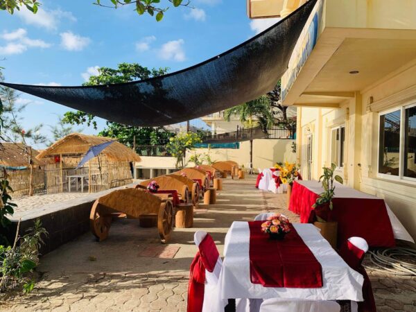 Outdoor dining area with thatched roofs and red tablecloths.