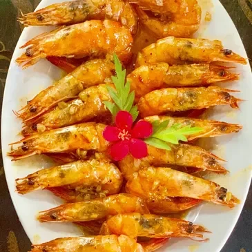 A plate of shrimp with a flower on the side.